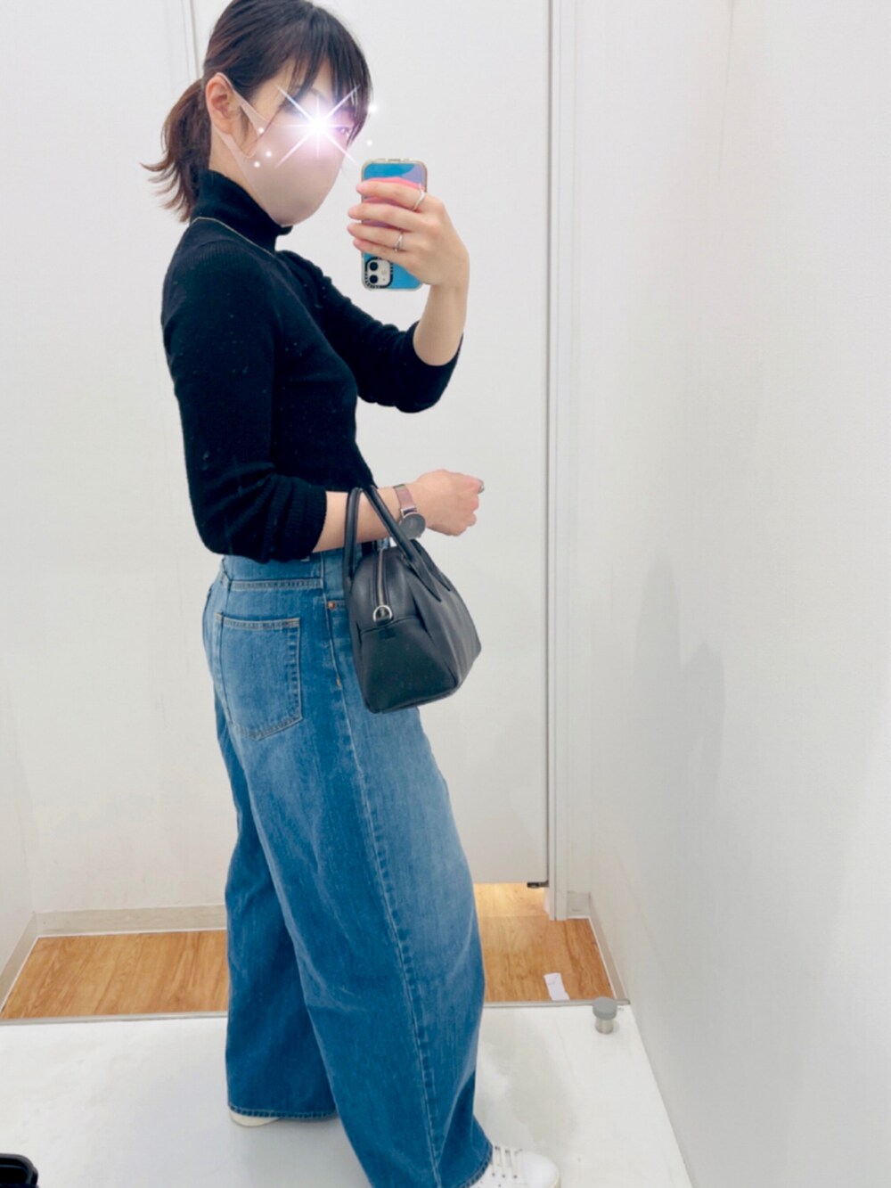 ブルー系のデニムパンツ、ホワイト系のスニーカー、ブラック系のアナログ腕時計を着用したレディースの秋コーディネートの2枚目の写真