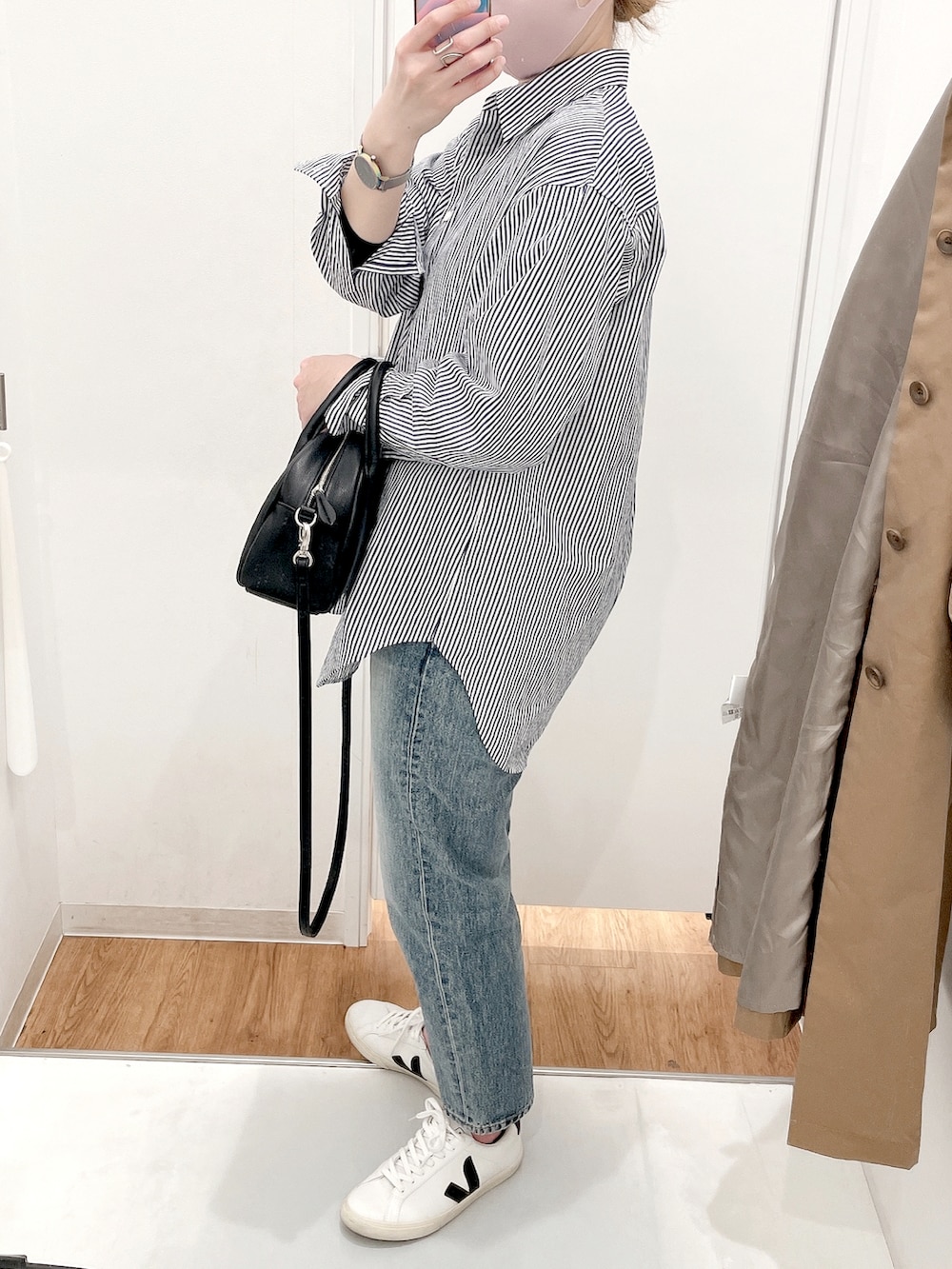 ブルー系のシャツ/ブラウス、ベージュ系のステンカラーコート、ブルー系のデニムパンツを着用したレディースの春コーディネートの2枚目の写真