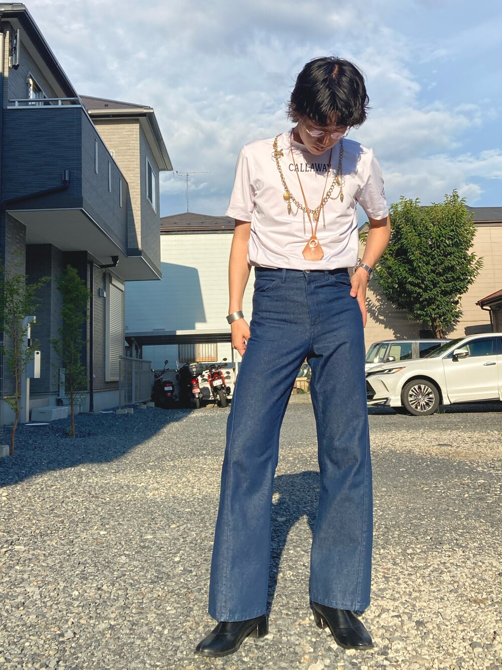 ホワイト系のTシャツ/カットソー、ブルー系のデニムパンツ、ブラック系のブーツを着用したメンズの夏コーディネートの2枚目の写真