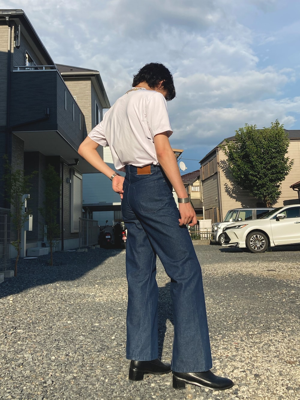 ホワイト系のTシャツ/カットソー、ブルー系のデニムパンツ、ブラック系のブーツを着用したメンズの夏コーディネートの3枚目の写真