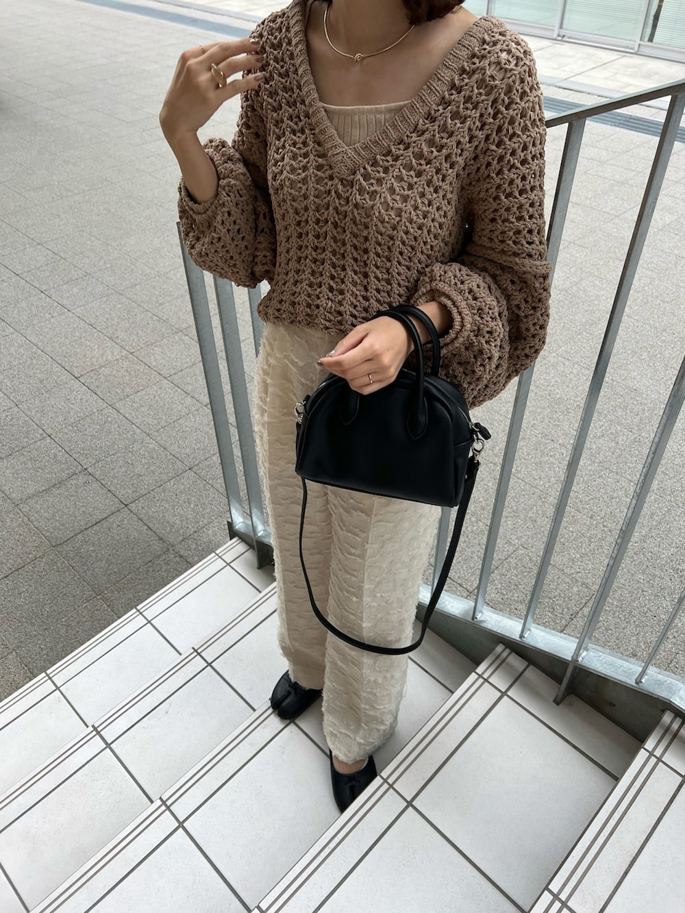ベージュ系のニット/セーター、ホワイト系のタンクトップ、ブラック系のショルダーバッグを着用したレディースの夏コーディネートの3枚目の写真