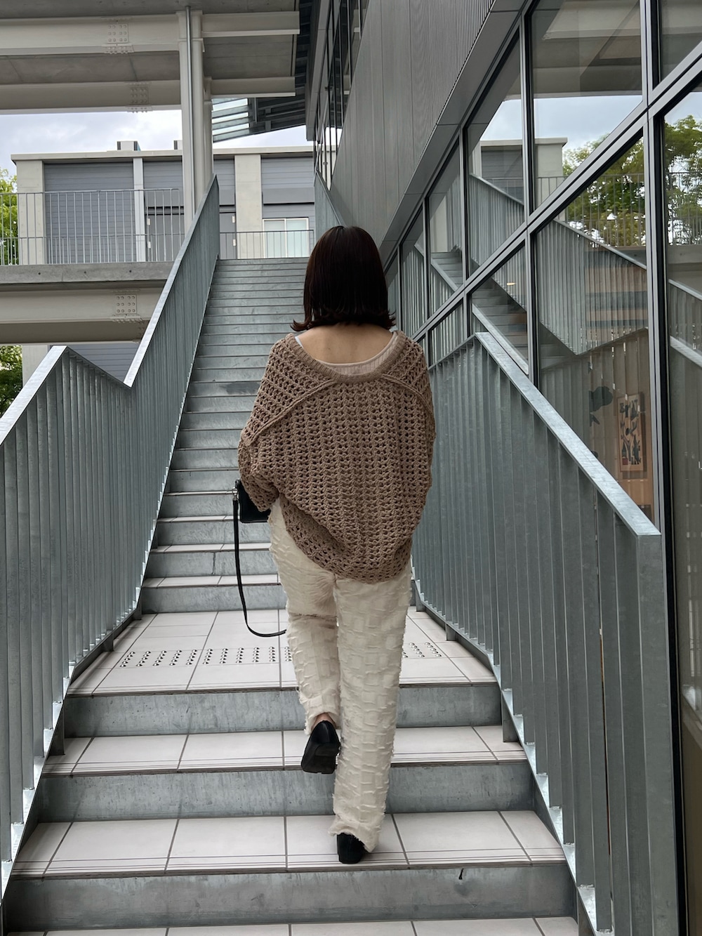 ベージュ系のニット/セーター、ホワイト系のタンクトップ、ブラック系のショルダーバッグを着用したレディースの夏コーディネートの2枚目の写真