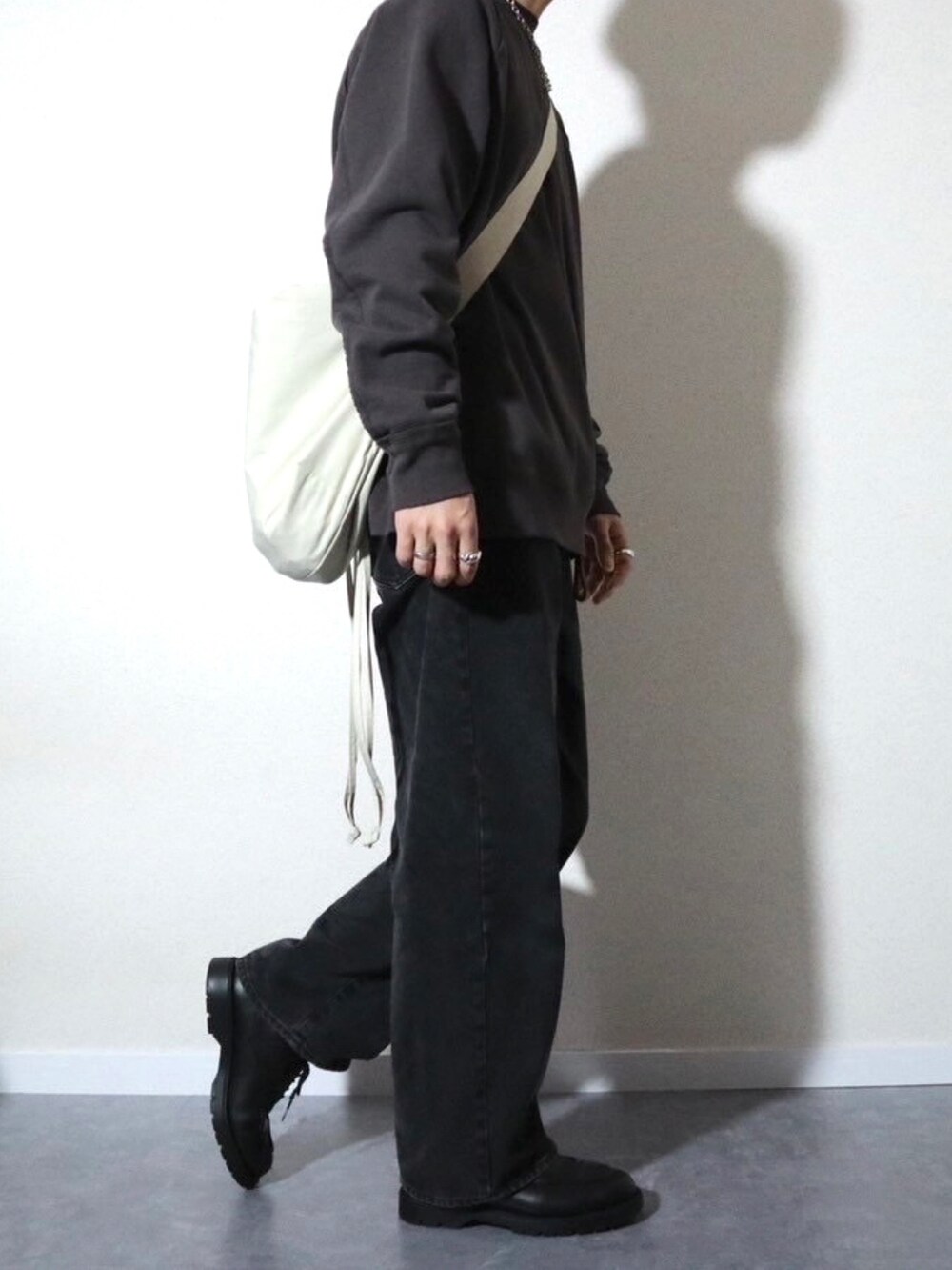 グレー系のスウェット、ブラック系のデニムパンツ、ブラック系のドレスシューズを着用したメンズの冬コーディネートの3枚目の写真