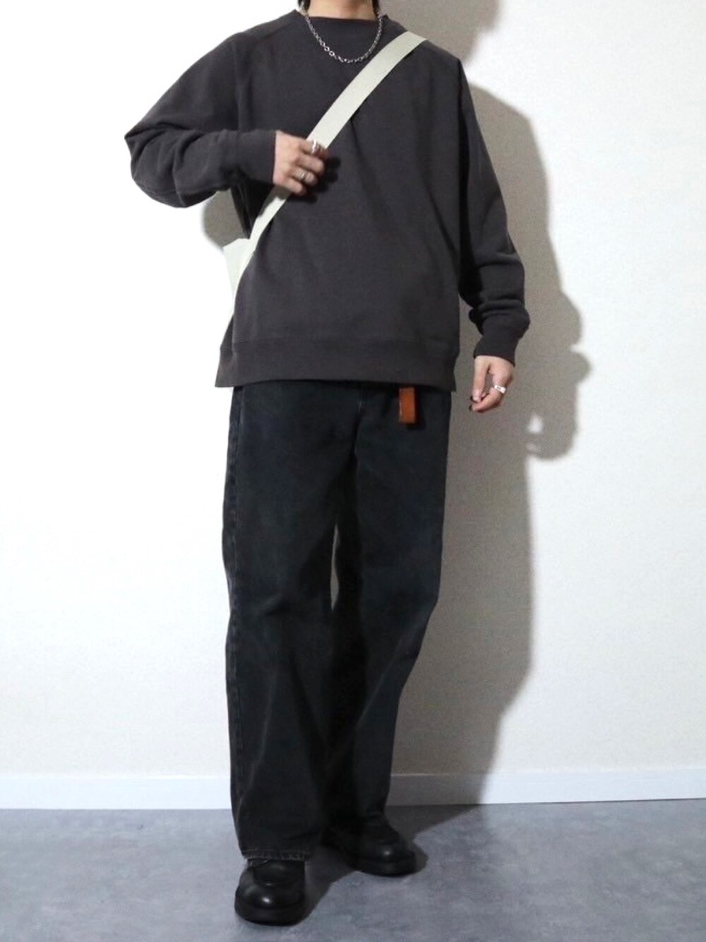 グレー系のスウェット、ブラック系のデニムパンツ、ブラック系のドレスシューズを着用したメンズの冬コーディネートの2枚目の写真