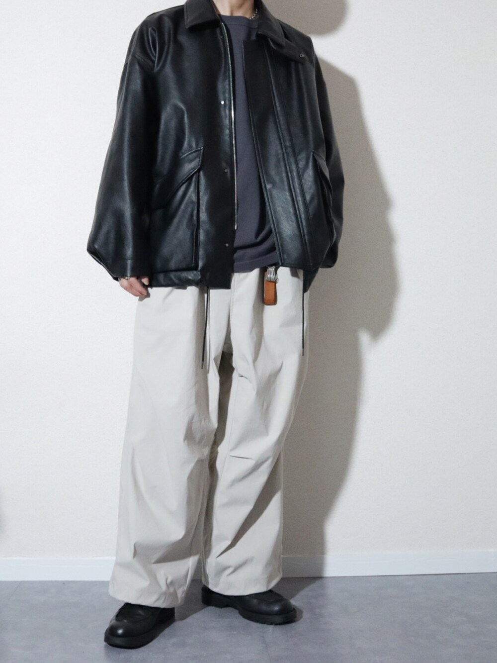 ブラック系のブルゾン、グレー系のその他パンツ、ブラック系のドレスシューズを着用したメンズの春コーディネートの2枚目の写真