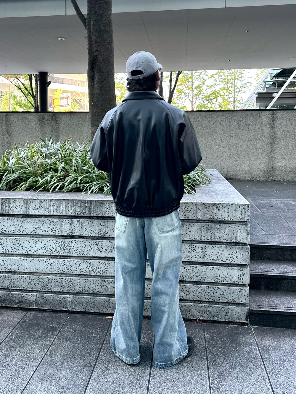 ブラック系のブルゾン、グレー系のニット/セーター、ブルー系のデニムパンツを着用したメンズの冬コーディネートの3枚目の写真