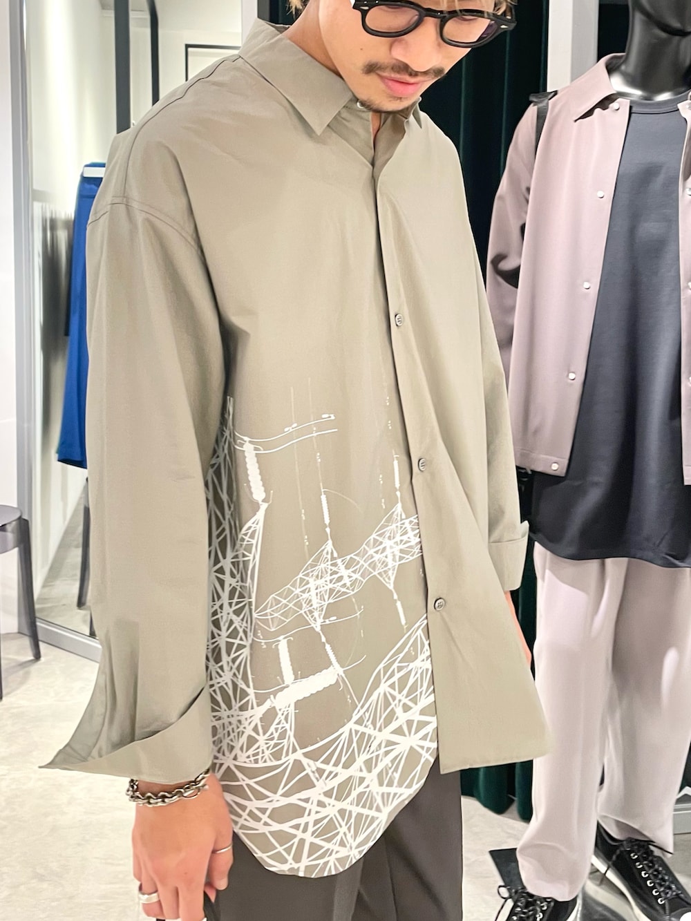 グレー系のシャツ/ブラウス、グレー系のスラックス、ブラック系のドレスシューズを着用したメンズの夏コーディネートの2枚目の写真
