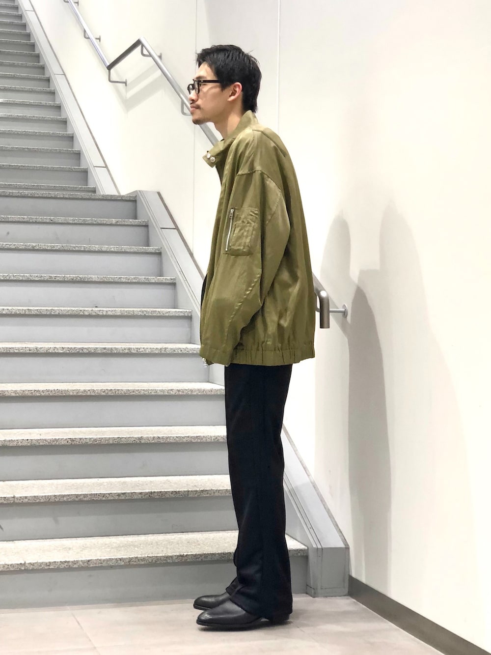 グリーン系のMA-1、グレー系のカーディガン/ボレロ、ブラック系のスラックスを着用したメンズの春コーディネートの2枚目の写真