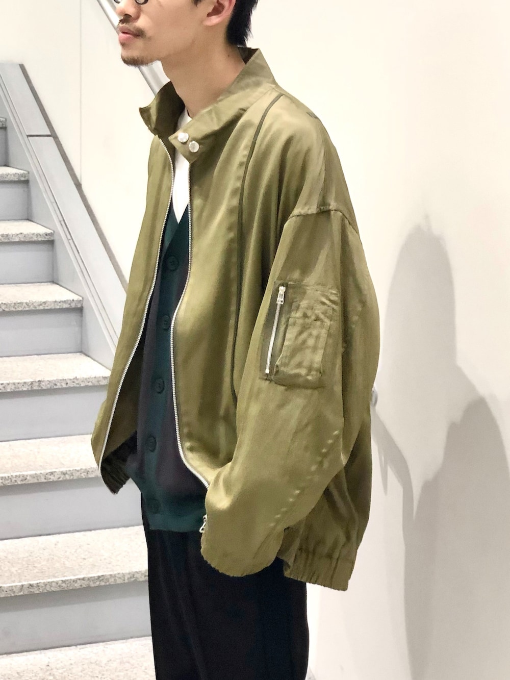 グリーン系のMA-1、グレー系のカーディガン/ボレロ、ブラック系のスラックスを着用したメンズの春コーディネートの3枚目の写真