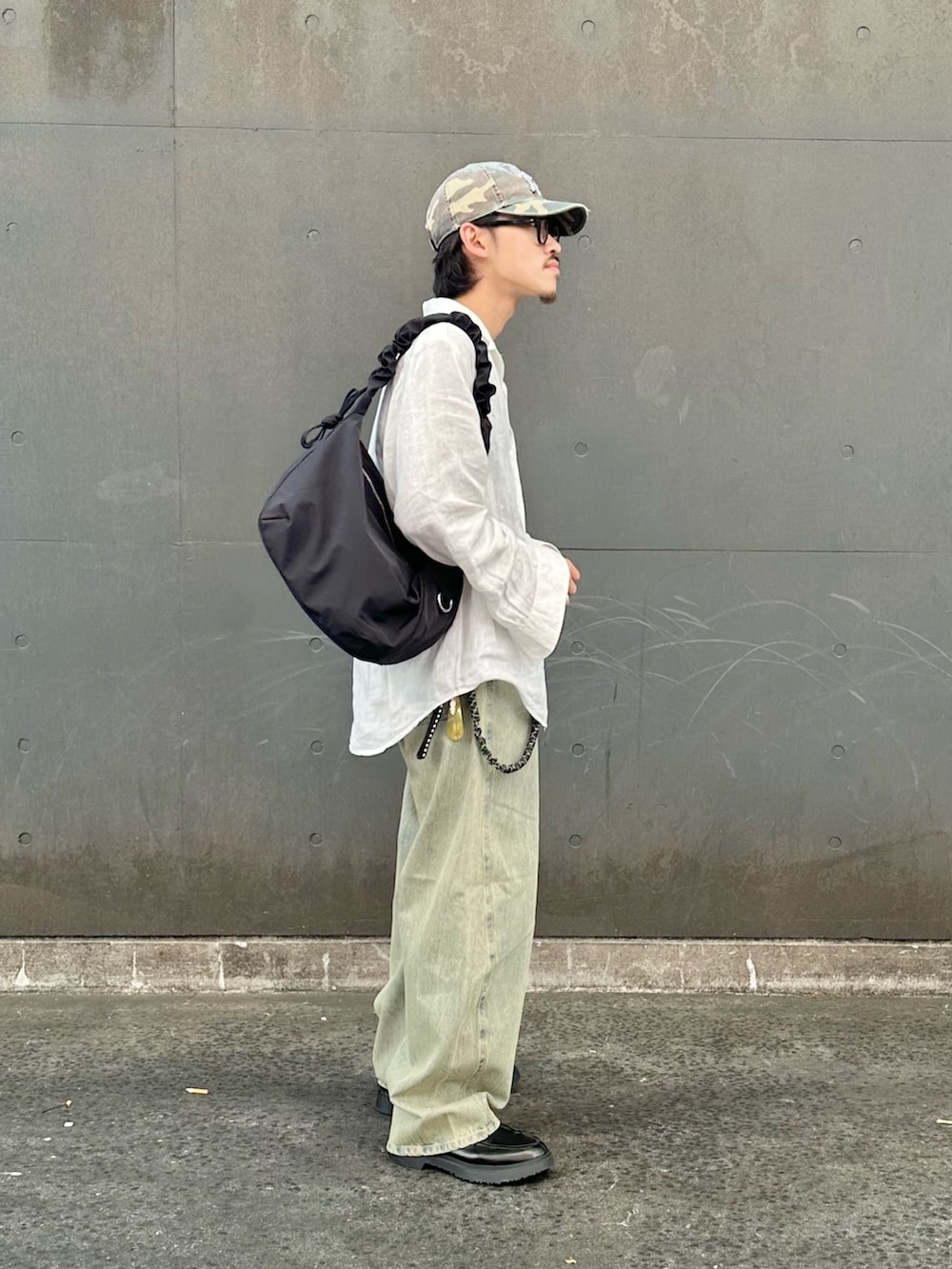 グリーン系のデニムパンツ、ブラック系のショルダーバッグを着用したメンズの夏コーディネートの2枚目の写真