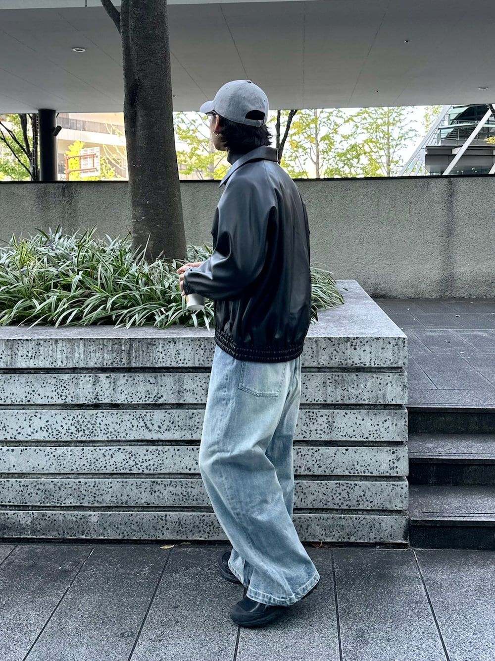 ブラック系のブルゾン、グレー系のニット/セーター、ブルー系のデニムパンツを着用したメンズの冬コーディネートの2枚目の写真