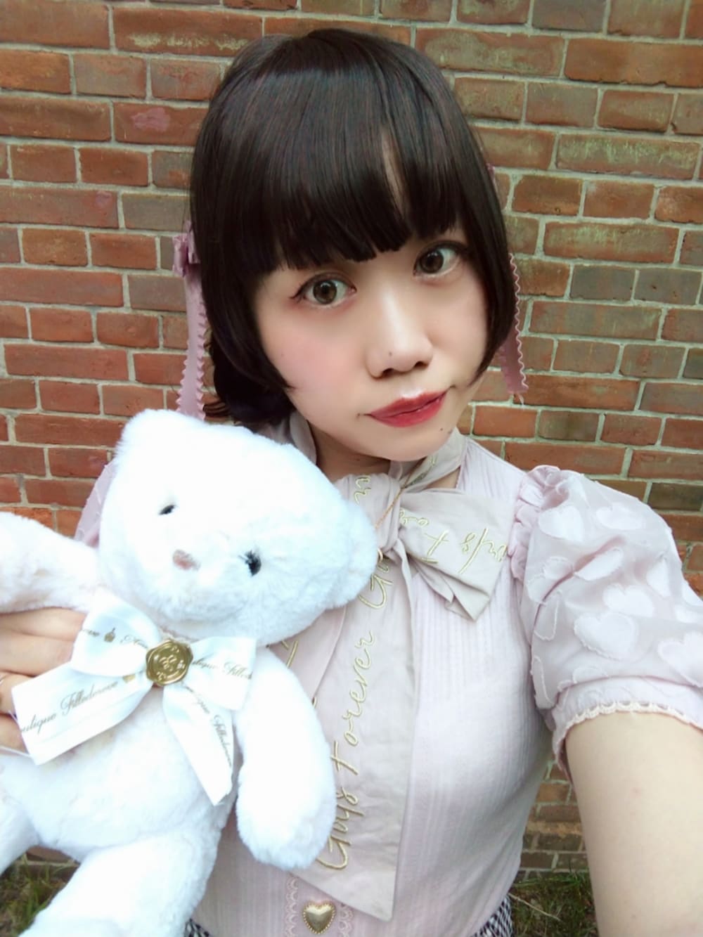 ブラック系のスカート、ピンク系のTシャツ/カットソー、ブラック系のパンプスを着用したレディースの夏コーディネートの2枚目の写真