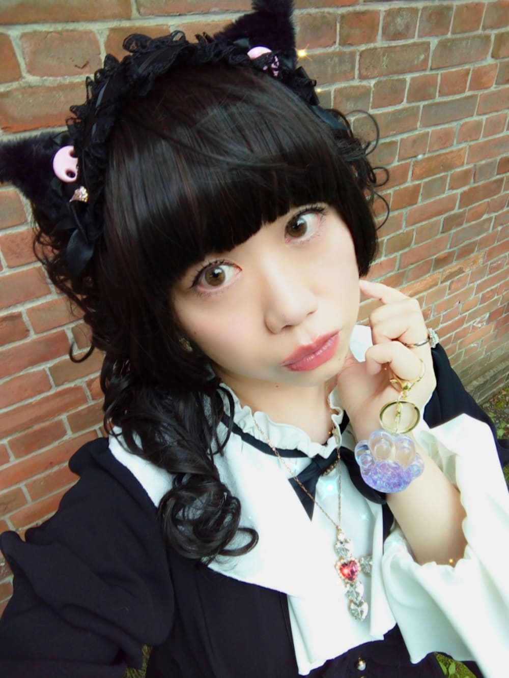 ブラック系のワンピース、ブラック系のパンプス、ピンク系のハンドバッグを着用したレディースの春コーディネートの5枚目の写真