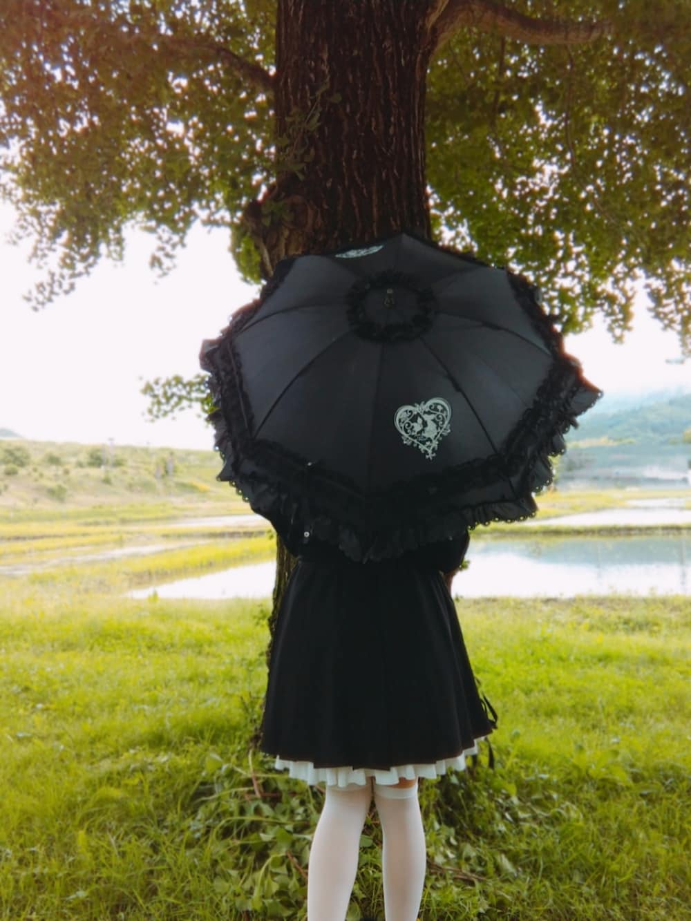 ブラック系のワンピース、ブラック系のパンプス、ピンク系のハンドバッグを着用したレディースの春コーディネートの3枚目の写真