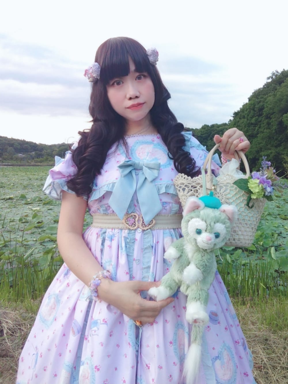 ピンク系のワンピース、ピンク系のパンプス、ベージュ系のかごバッグを着用したレディースの夏コーディネートの2枚目の写真
