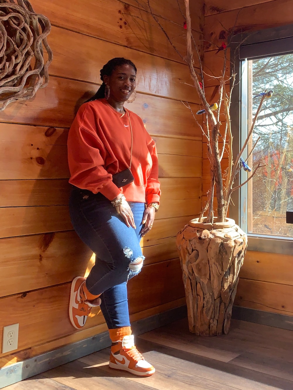 オレンジ系のスニーカー、ブラウン系のバッグ、オレンジ系のスウェットを着用したレディースの冬コーディネートの2枚目の写真