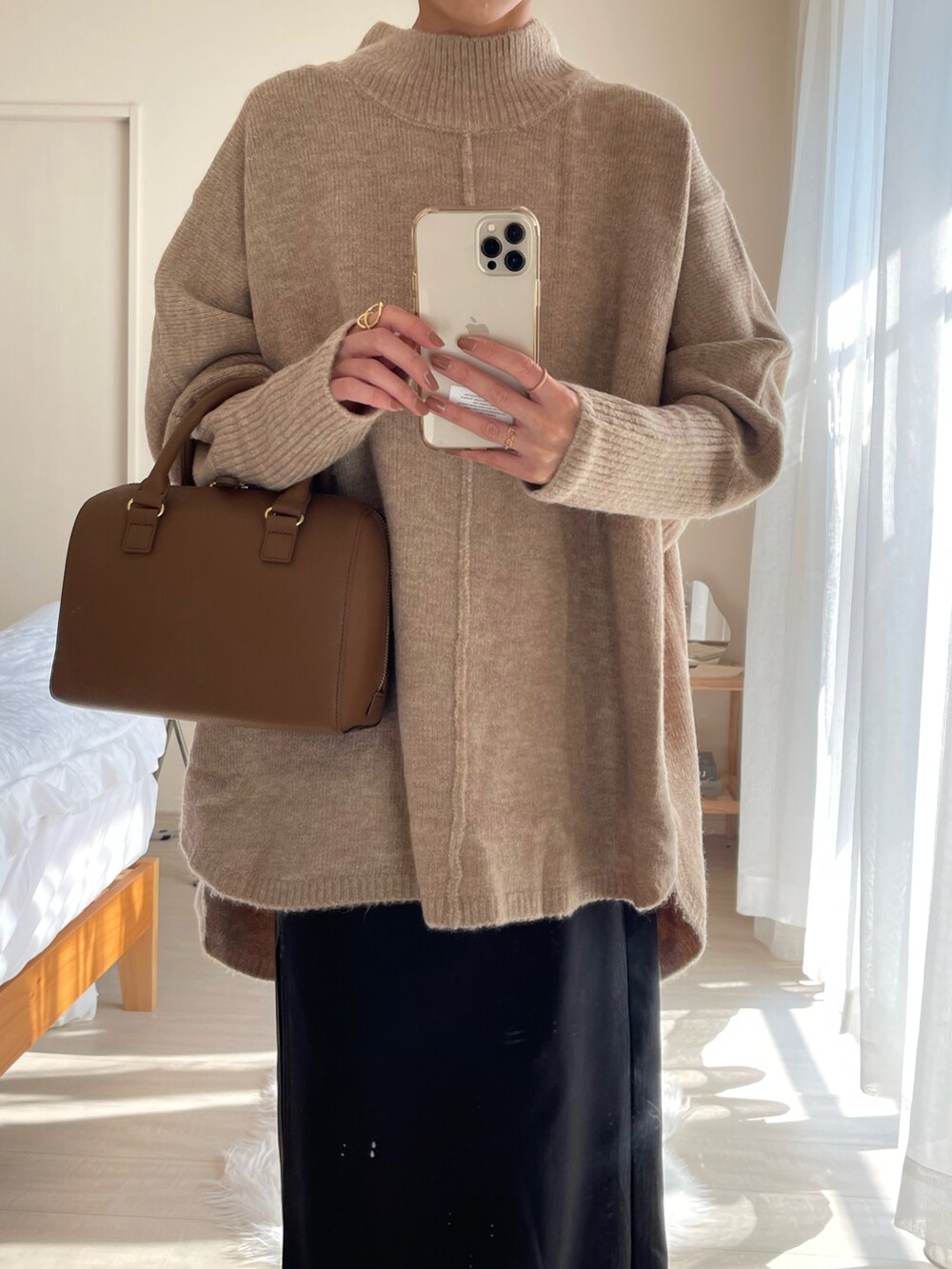 ブラウン系のバッグ、ベージュ系のニット/セーター、ブラック系のスカートを着用したレディースの秋コーディネートの2枚目の写真