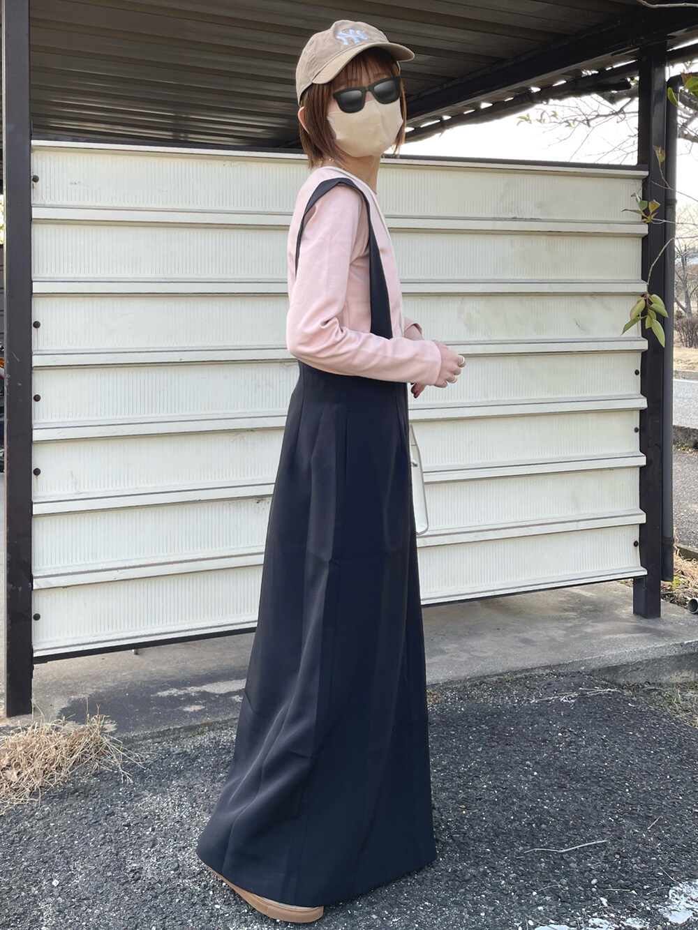 ブラック系のジャンパースカート、ピンク系のTシャツ/カットソー、ホワイト系のショルダーバッグを着用したレディースの冬コーディネートの3枚目の写真