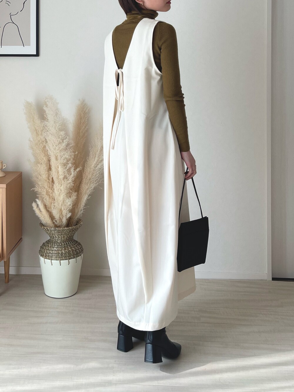 ホワイト系のジャンパースカート、ブラック系のショルダーバッグ、ブラック系のブーツを着用したレディースの冬コーディネートの2枚目の写真