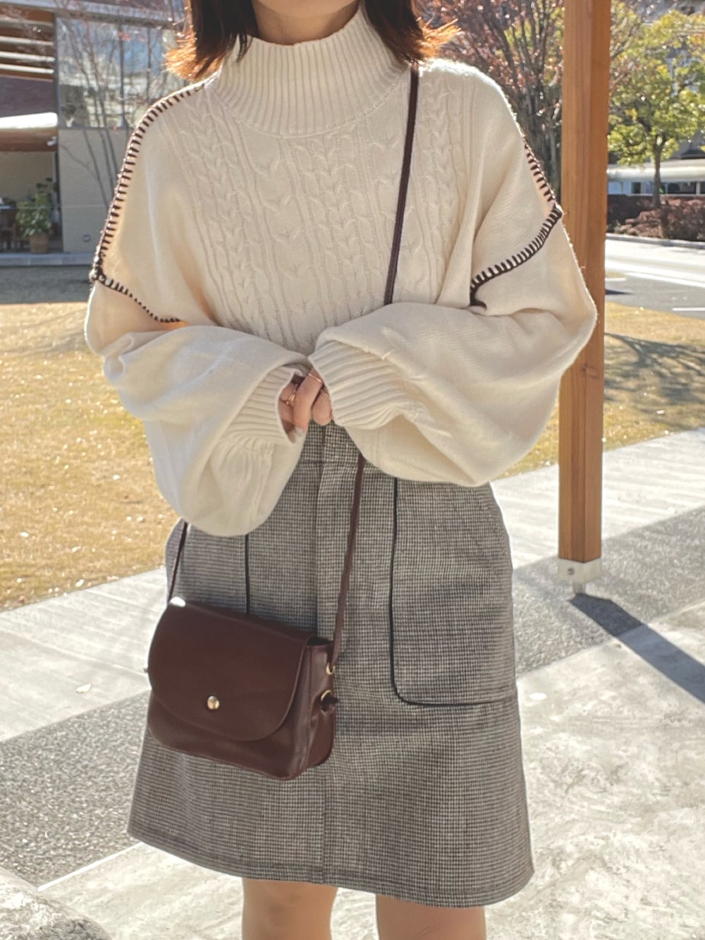 ホワイト系のニット/セーター、ブラウン系のスカート、レッド系のショルダーバッグを着用したレディースの冬コーディネートの2枚目の写真