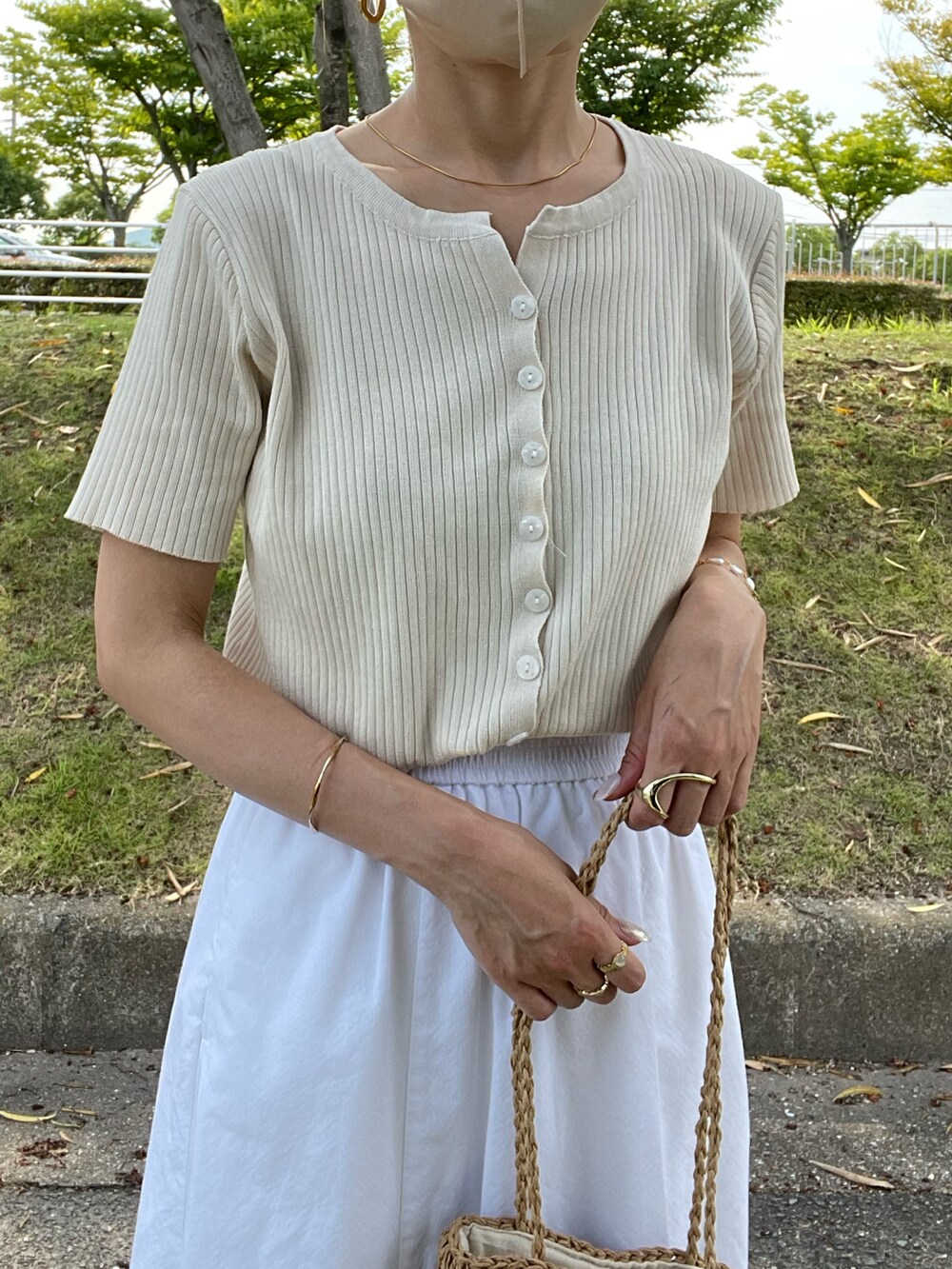 ベージュ系のトップス、ベージュ系のトートバッグ、ホワイト系のスカートを着用したレディースの夏コーディネートの3枚目の写真