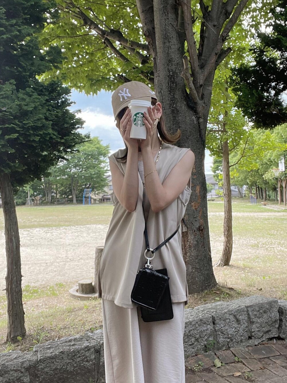 ベージュ系のベスト、ブラック系のショルダーバッグ、ベージュ系のワンピース/ドレスを着用したレディースの夏コーディネートの2枚目の写真