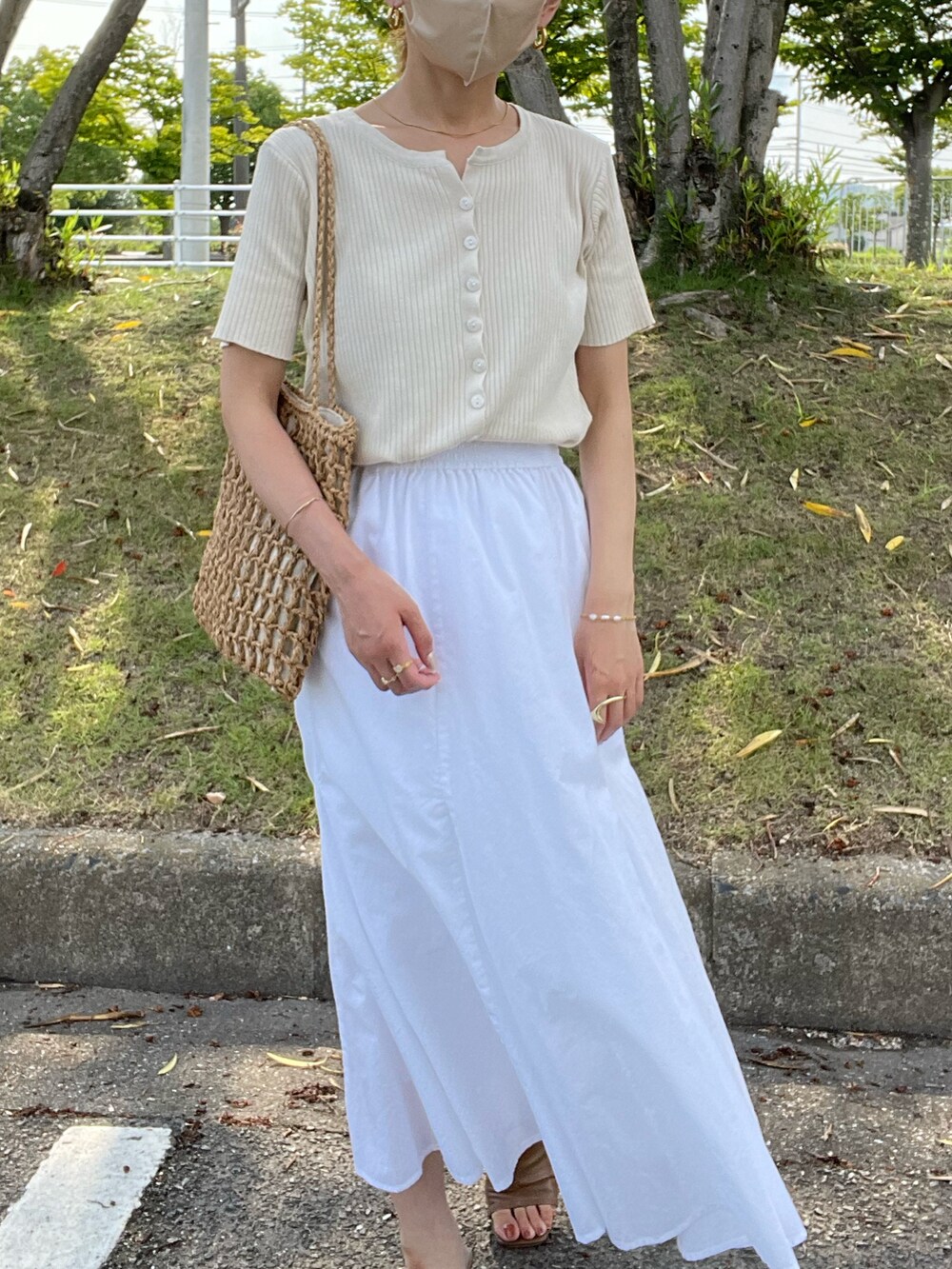 ベージュ系のトップス、ベージュ系のトートバッグ、ホワイト系のスカートを着用したレディースの夏コーディネートの2枚目の写真