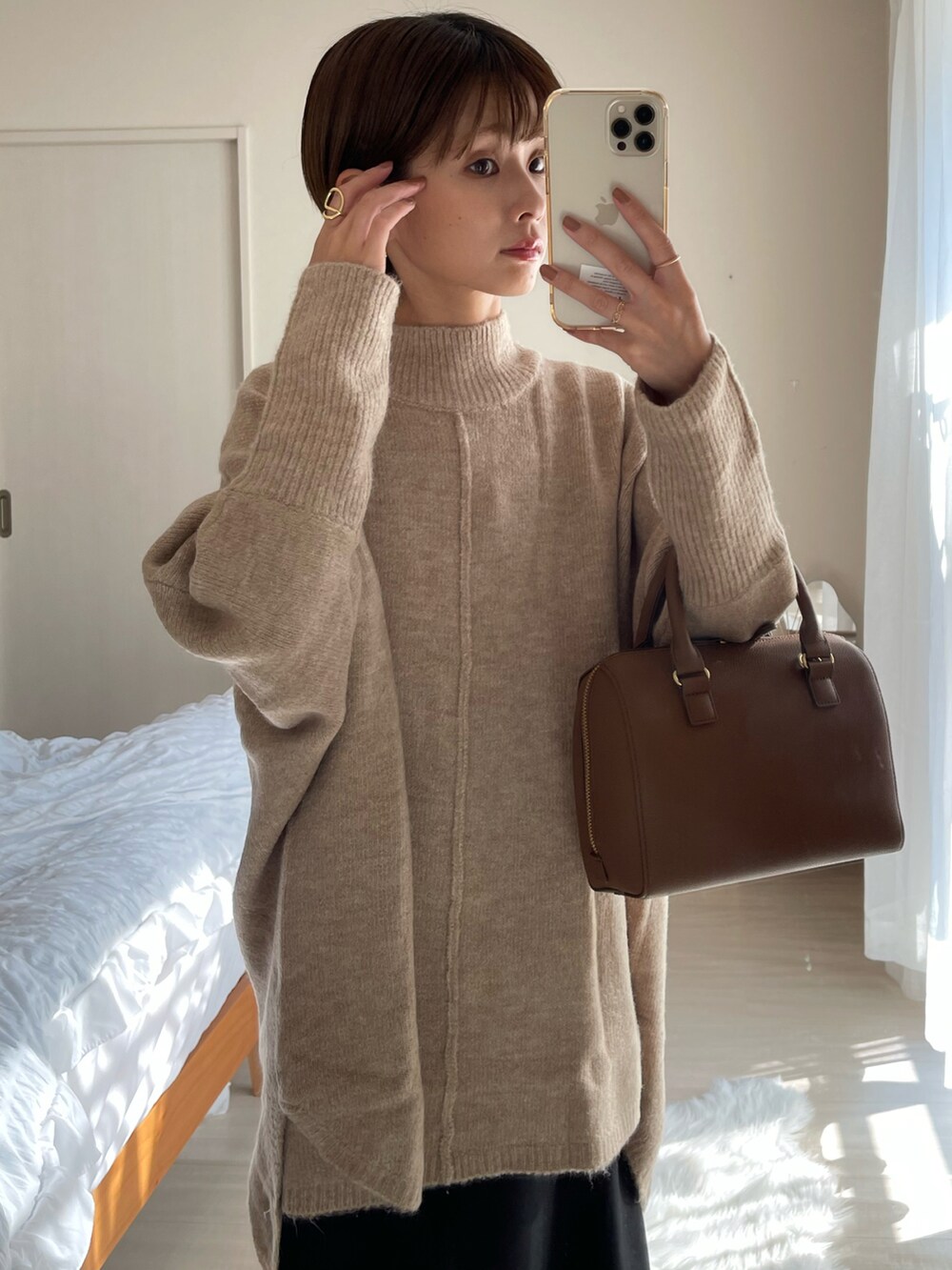 ブラウン系のバッグ、ベージュ系のニット/セーター、ブラック系のスカートを着用したレディースの秋コーディネートの3枚目の写真