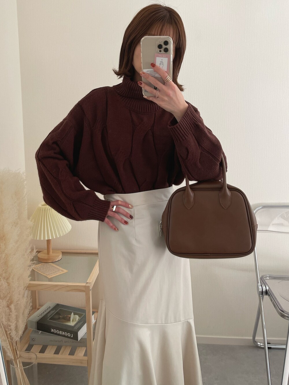 ブラウン系のニット/セーター、ブラウン系のボストンバッグ、ホワイト系のスカートを着用したレディースの冬コーディネートの2枚目の写真