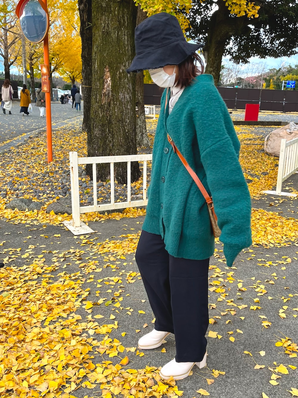 グリーン系のニット/セーター、ブラック系のスラックス、ホワイト系のブーツを着用したレディースの秋コーディネートの2枚目の写真