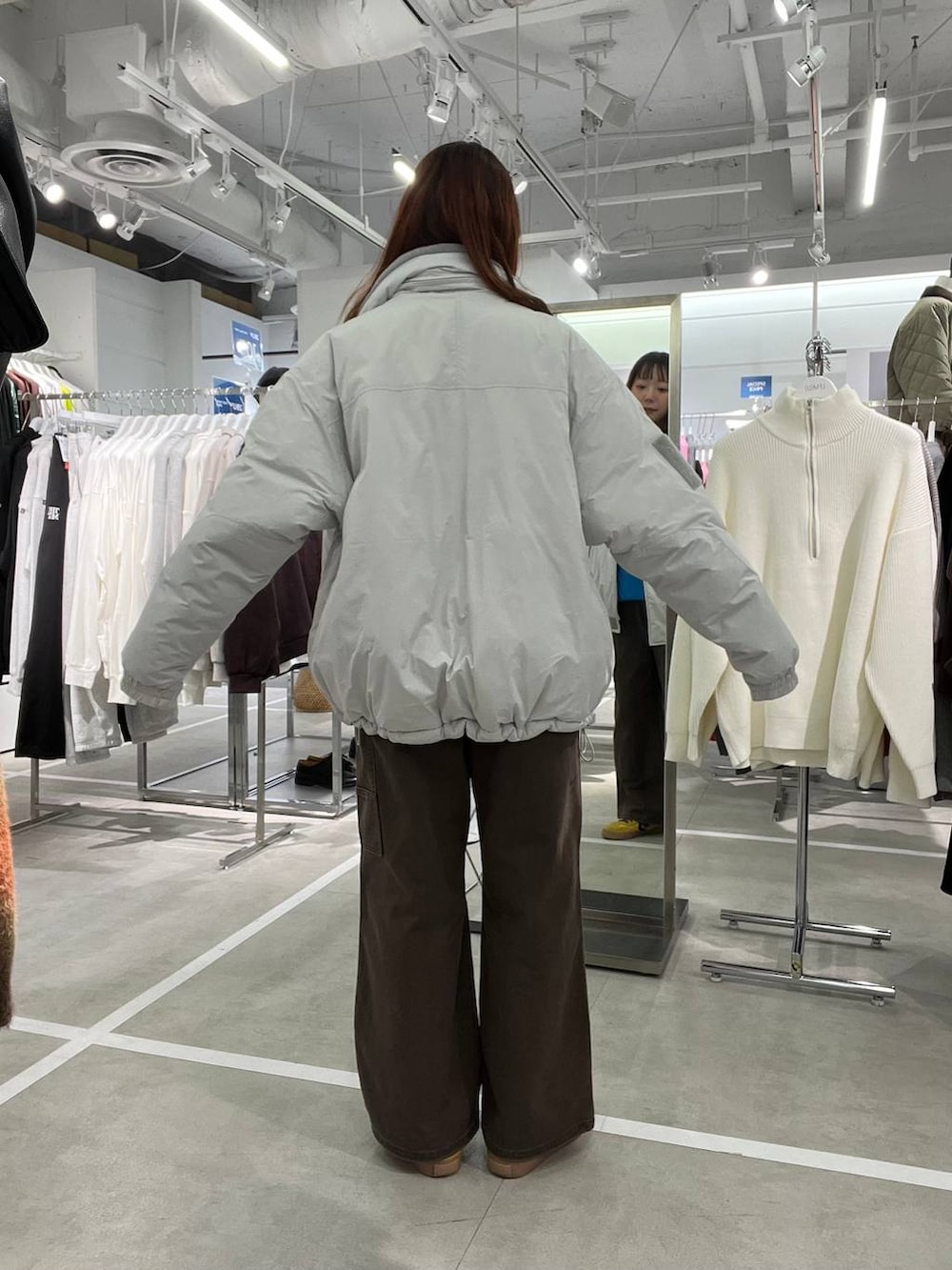 グレー系のダウンジャケット/コート、ブラウン系のデニムパンツ、ブルー系のニット/セーターを着用したメンズの冬コーディネートの3枚目の写真