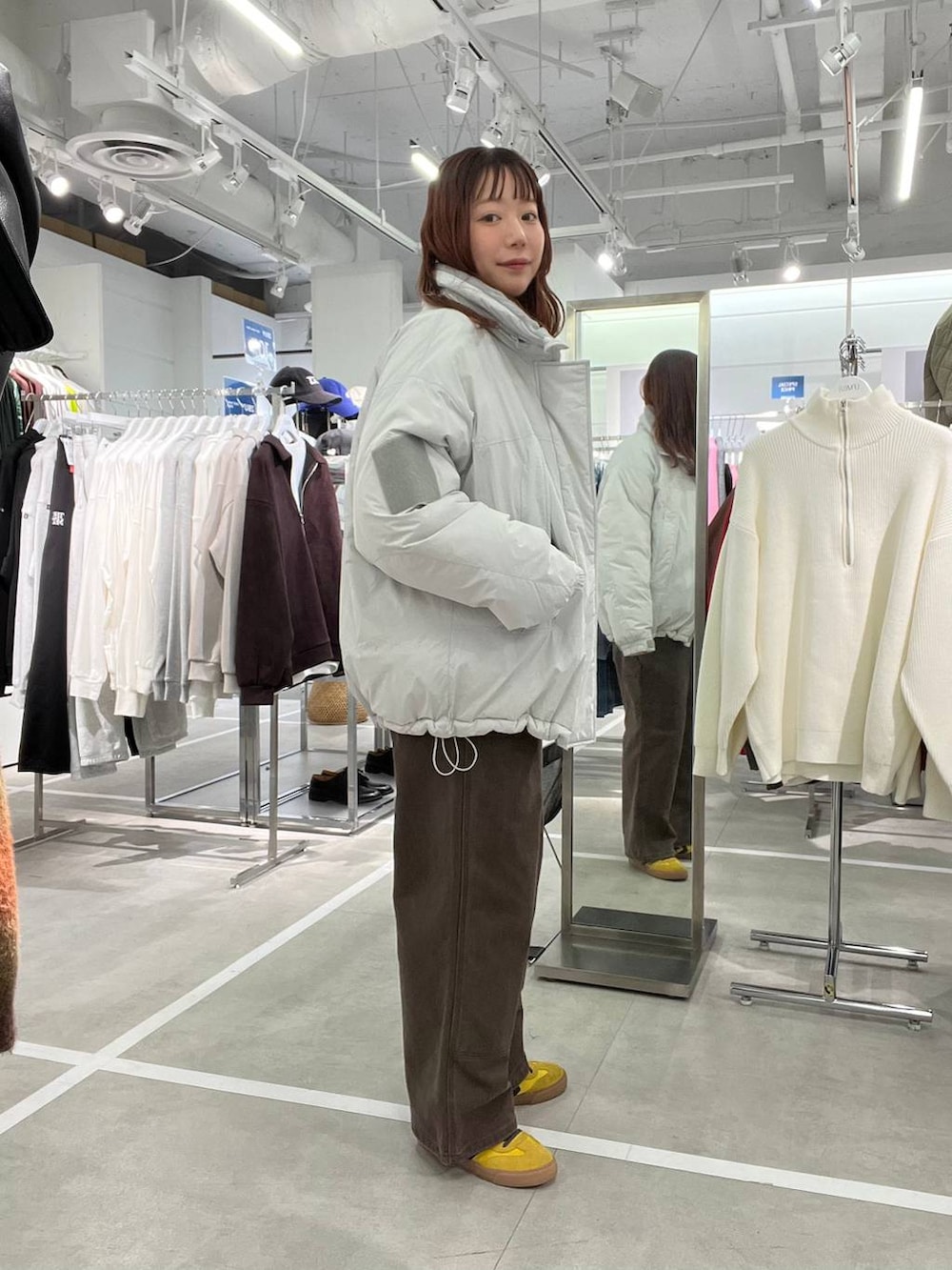 グレー系のダウンジャケット/コート、ブラウン系のデニムパンツ、ブルー系のニット/セーターを着用したメンズの冬コーディネートの2枚目の写真