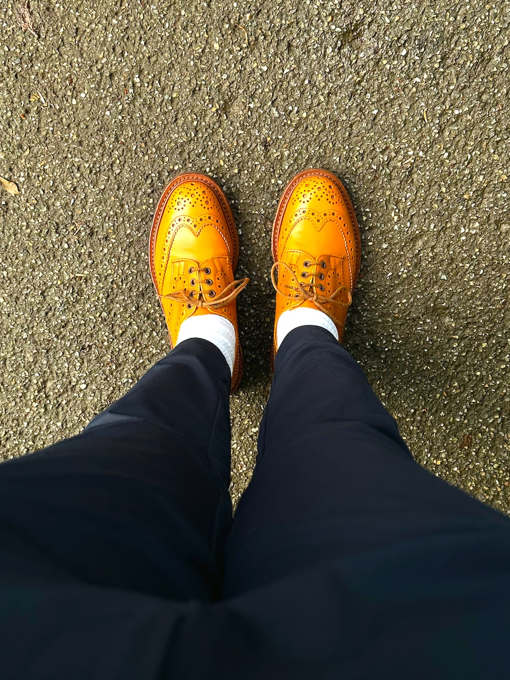 オレンジ系のドレスシューズ、ブルー系のスラックス、ホワイト系のTシャツ/カットソーを着用したメンズの夏コーディネートの2枚目の写真
