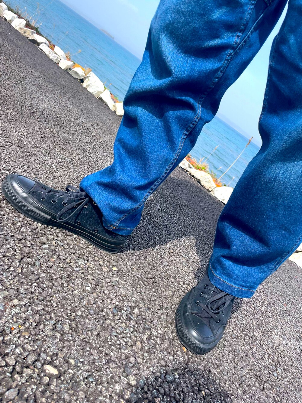 ブラック系のスニーカー、ブルー系のデニムパンツ、ホワイト系のTシャツ/カットソーを着用したメンズの春コーディネートの2枚目の写真