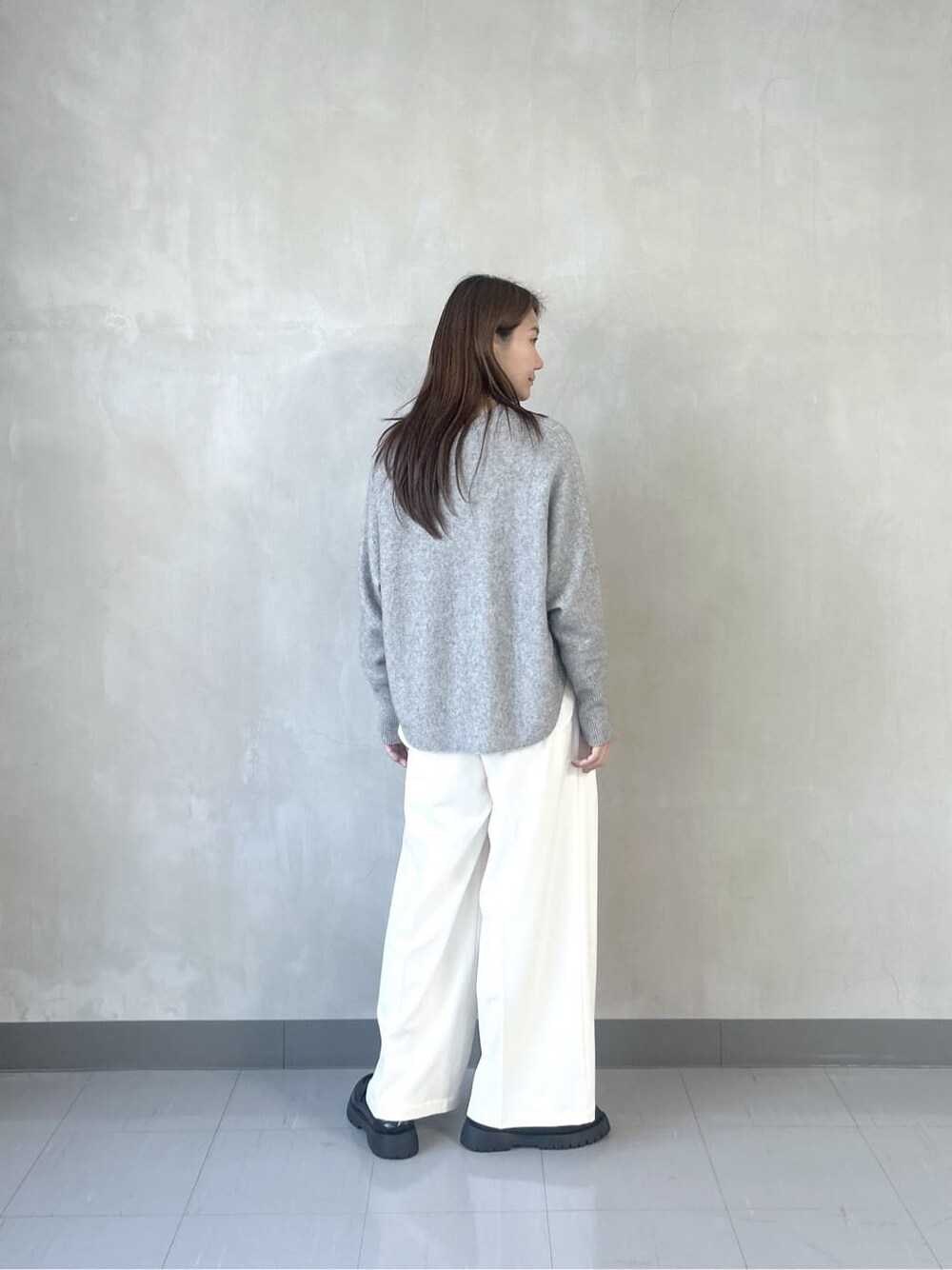 グレー系のニット/セーター、ホワイト系のシャツ/ブラウス、ホワイト系のその他パンツを着用したレディースの秋コーディネートの5枚目の写真