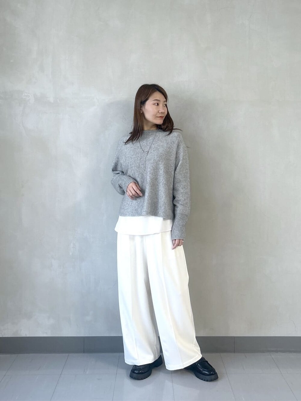グレー系のニット/セーター、ホワイト系のシャツ/ブラウス、ホワイト系のその他パンツを着用したレディースの秋コーディネートの2枚目の写真