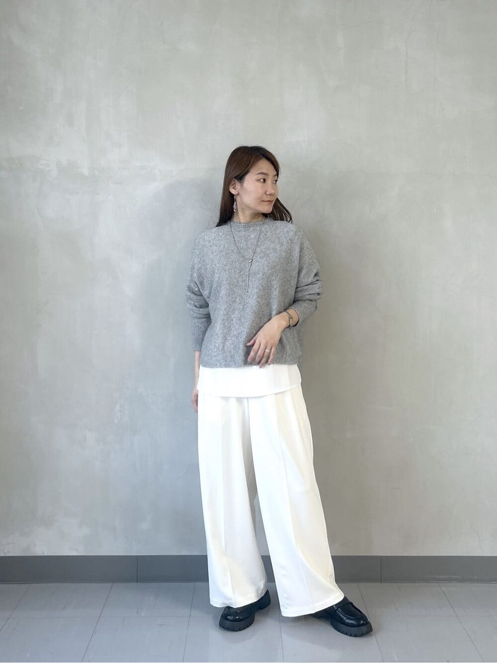 グレー系のニット/セーター、ホワイト系のシャツ/ブラウス、ホワイト系のその他パンツを着用したレディースの秋コーディネートの3枚目の写真