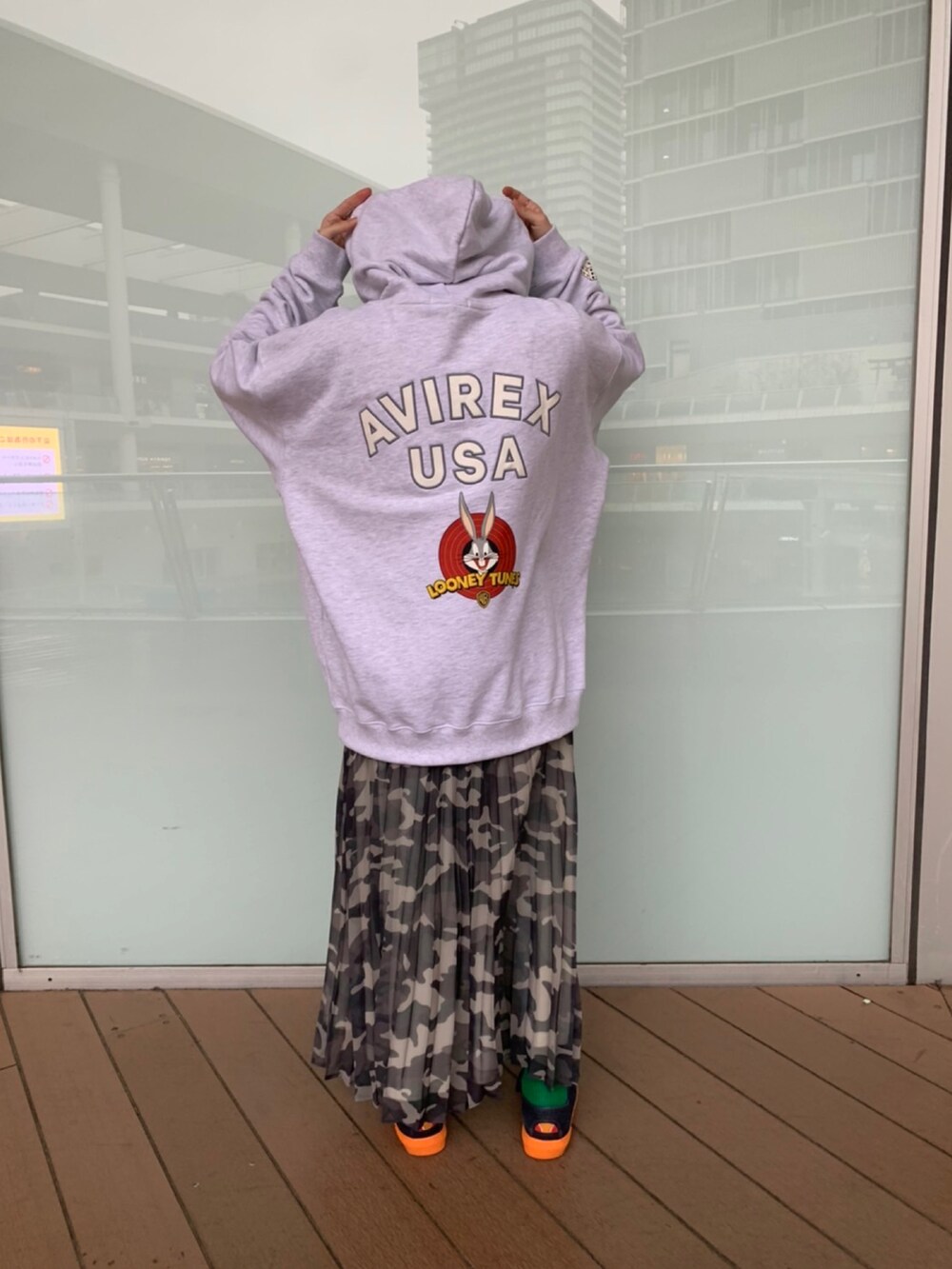 グレー系のパーカー、グレー系のスカート、ホワイト系のキャップを着用したレディースの冬コーディネートの2枚目の写真