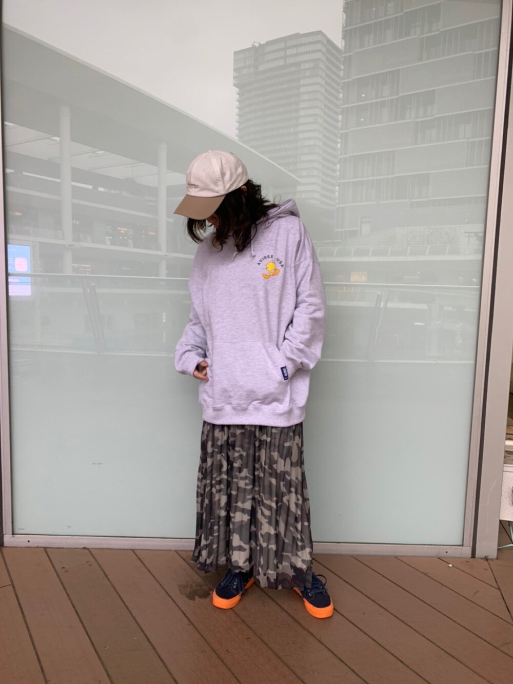 グレー系のパーカー、グレー系のスカート、ホワイト系のキャップを着用したレディースの冬コーディネートの3枚目の写真