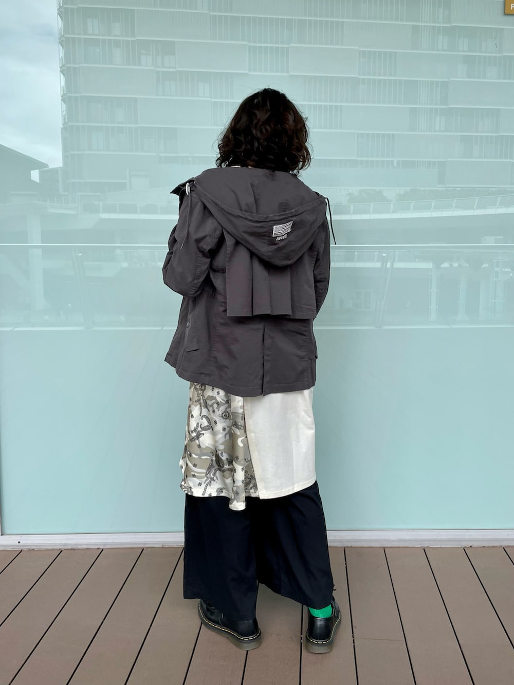 グレー系のマウンテンパーカー、ホワイト系のワンピース、ブラック系のその他パンツを着用したレディースの春コーディネートの2枚目の写真