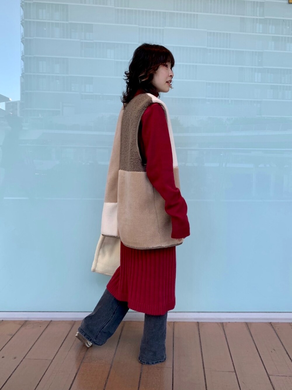 レッド系のワンピース/ドレス、ホワイト系のベスト、ブラック系のデニムパンツを着用したレディースの秋コーディネートの2枚目の写真