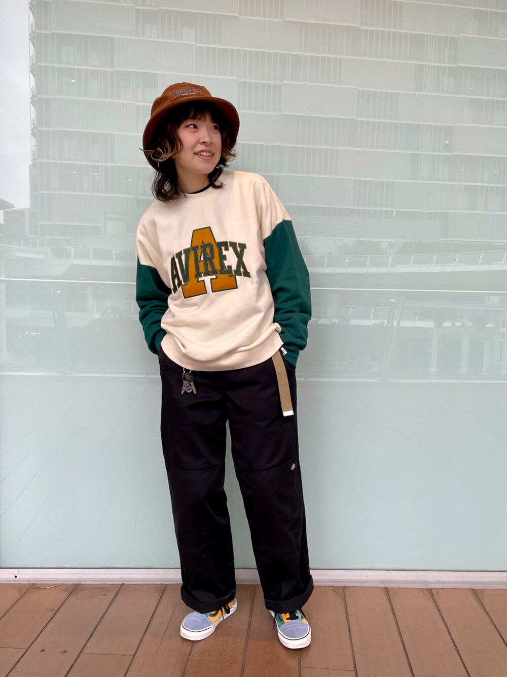 グリーン系のスウェット、ブラック系のチノパンツ、ブラウン系のハットを着用したレディースの秋コーディネートの2枚目の写真