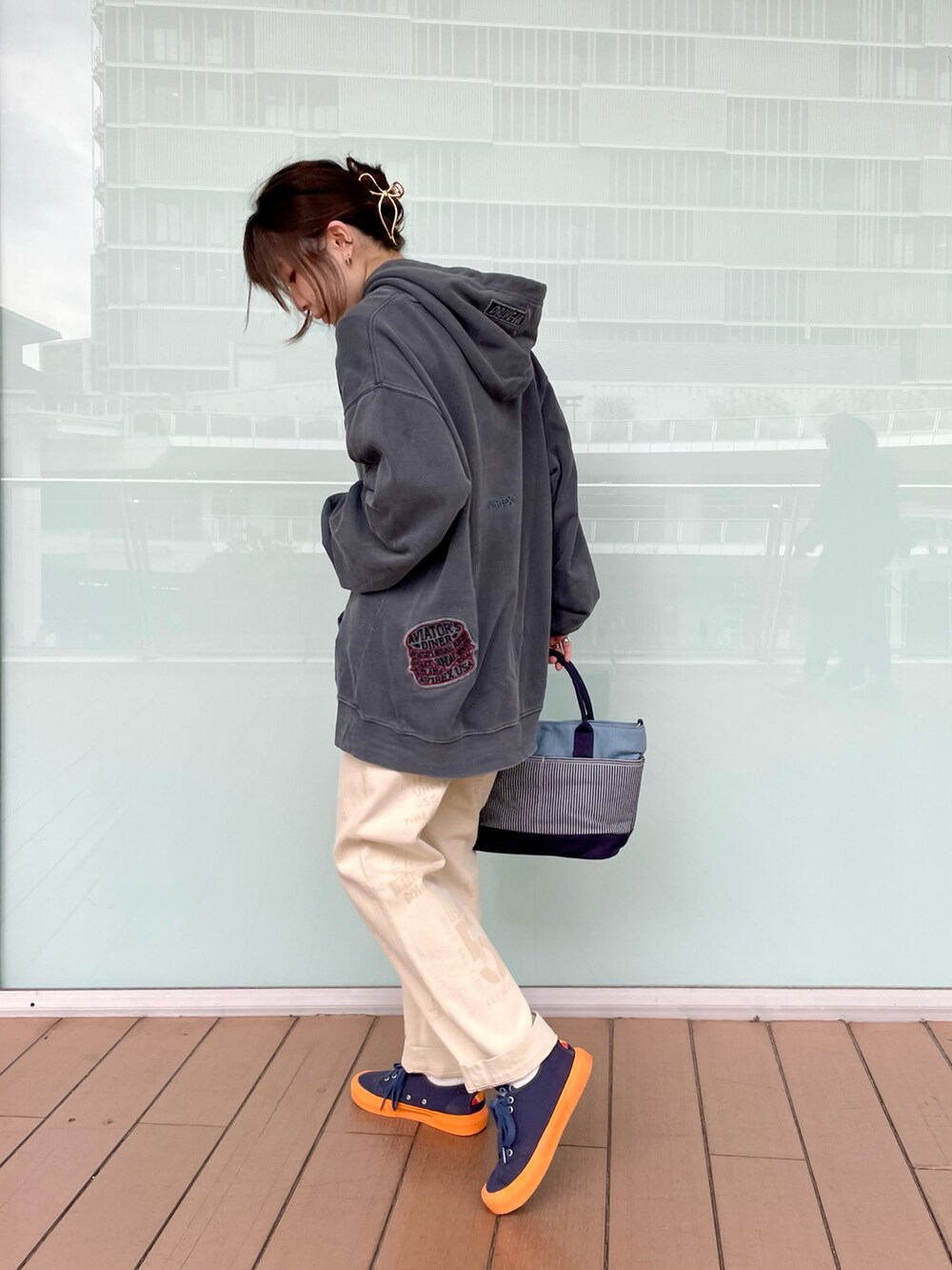 ブラック系のパーカー、その他のトートバッグ、ホワイト系のチノパンツを着用したレディースの冬コーディネートの2枚目の写真