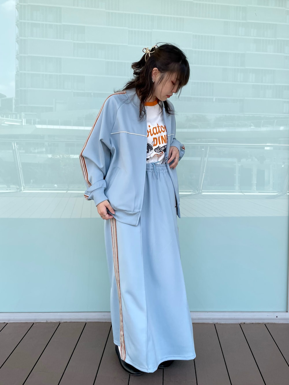 ブルー系のジャージ、ブルー系のスカート、オレンジ系のTシャツ/カットソーを着用したレディースの春コーディネートの2枚目の写真