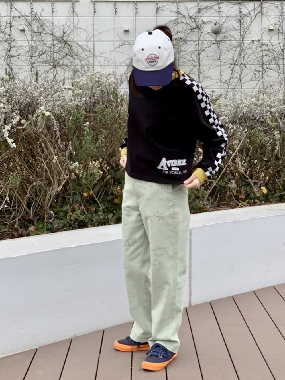 ブラック系のTシャツ/カットソー、グリーン系のチノパンツ、ホワイト系のキャップを着用したレディースの冬コーディネートの2枚目の写真