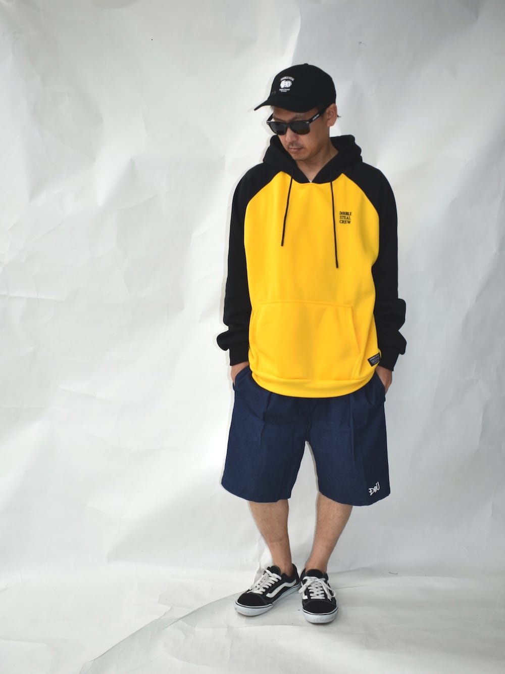 ブラック系のスニーカー、ブルー系のデニムパンツ、イエロー系のパーカーを着用したメンズの冬コーディネートの4枚目の写真