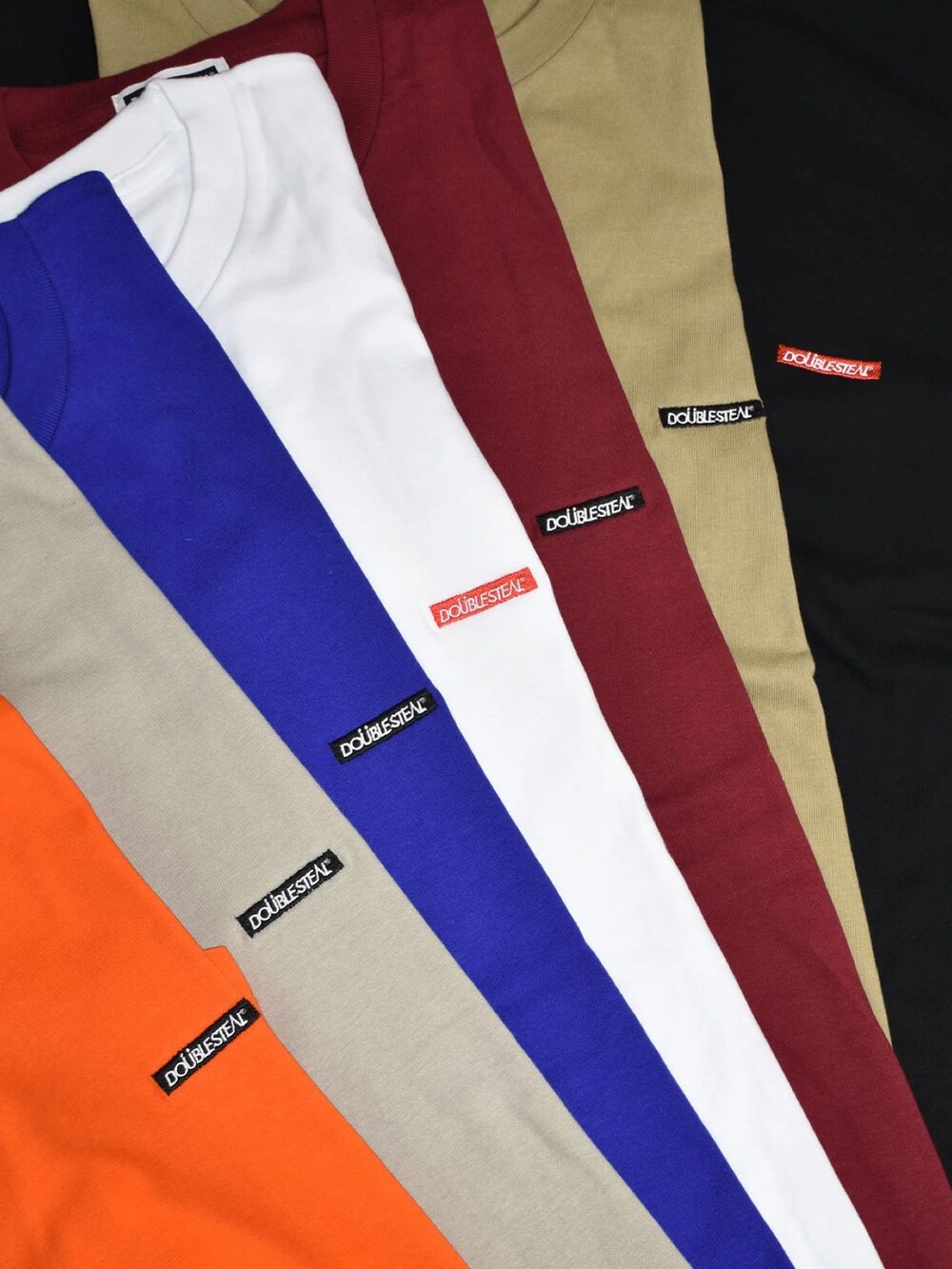 ブラック系のスニーカー、ブルー系のデニムパンツ、オレンジ系のTシャツ/カットソーを着用したメンズの夏コーディネートの2枚目の写真