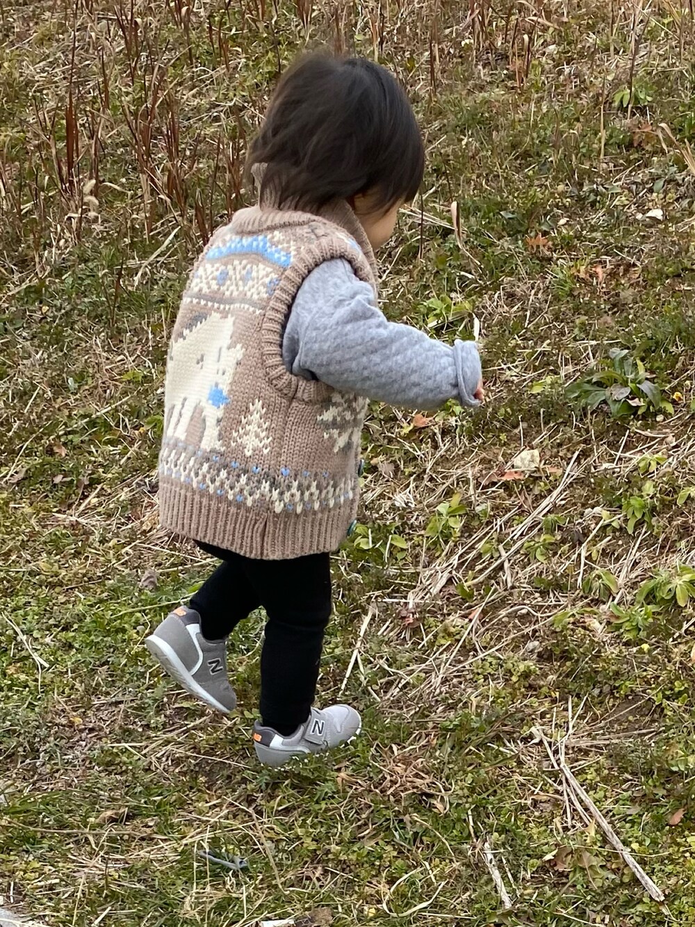 ベージュ系のベスト、ブラック系のパンツ、グレー系のスニーカーを着用したキッズの冬コーディネートの3枚目の写真