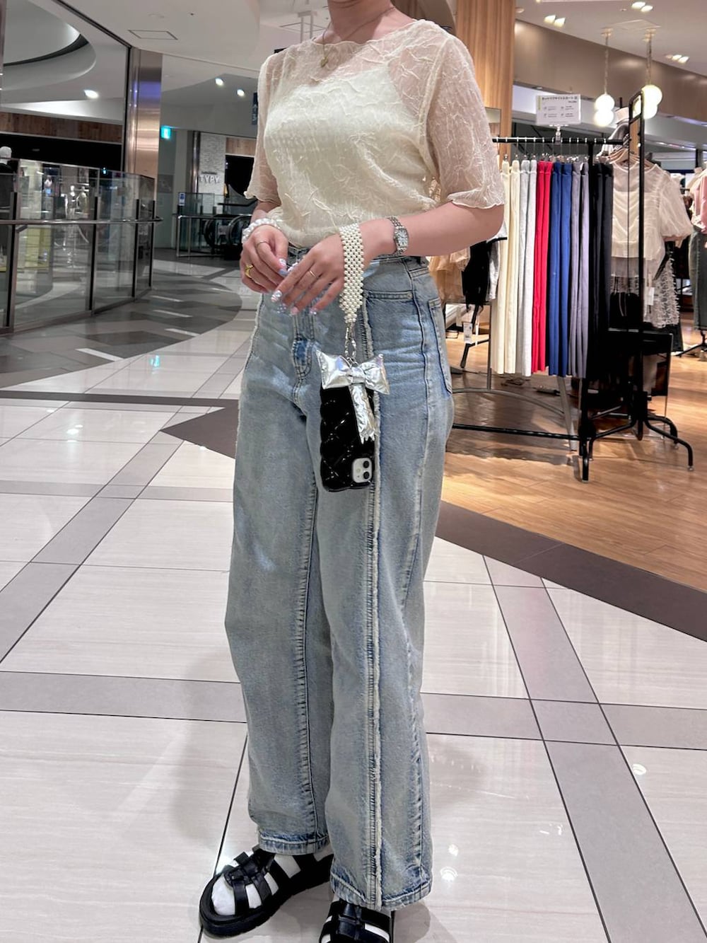 ホワイト系のTシャツ/カットソー、ブラック系のスニーカー、ブルー系のデニムパンツを着用したレディースの夏コーディネートの3枚目の写真