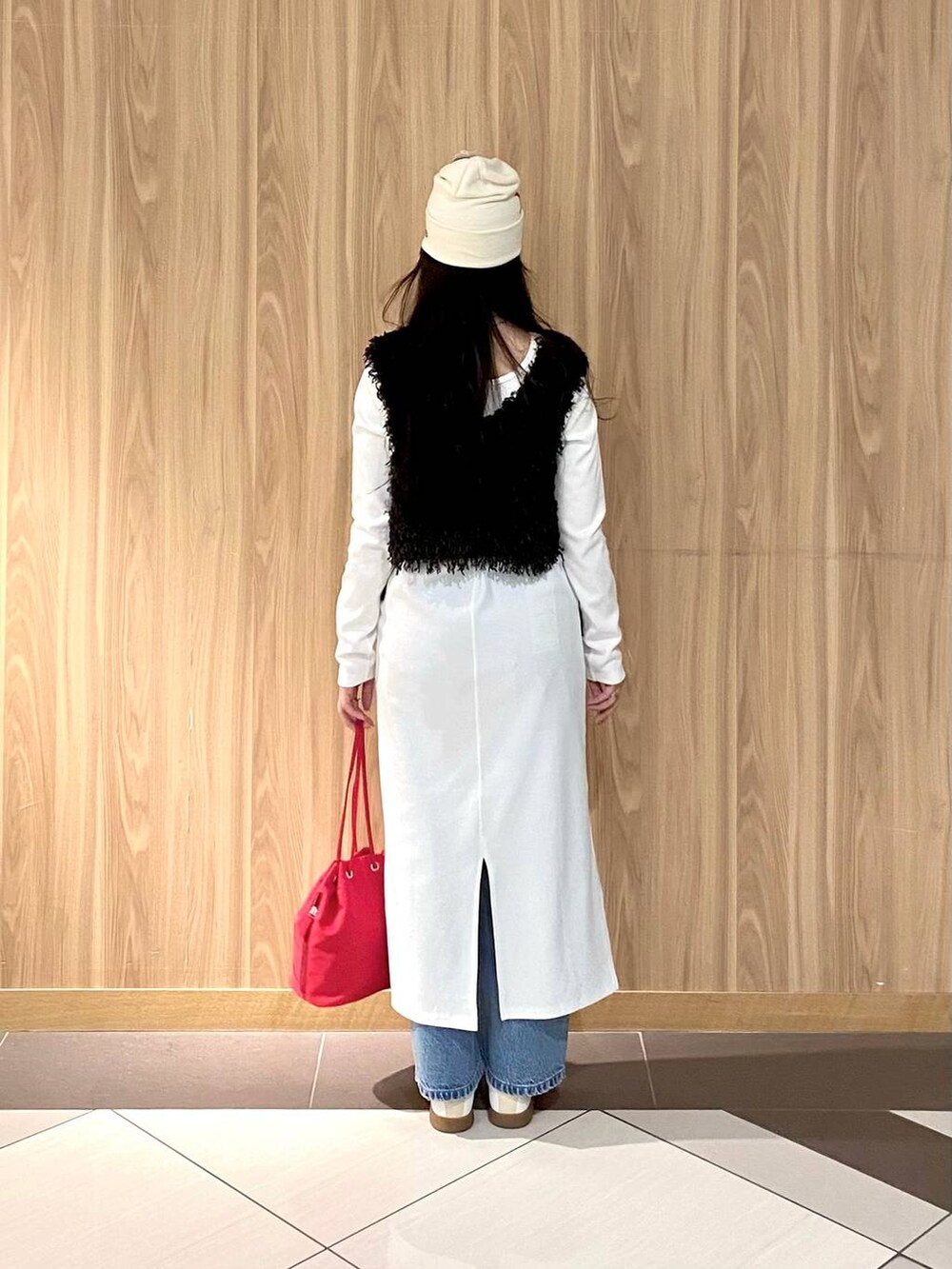 レッド系のハンドバッグ、ブルー系のデニムパンツ、ホワイト系のスニーカーを着用したレディースの冬コーディネートの3枚目の写真